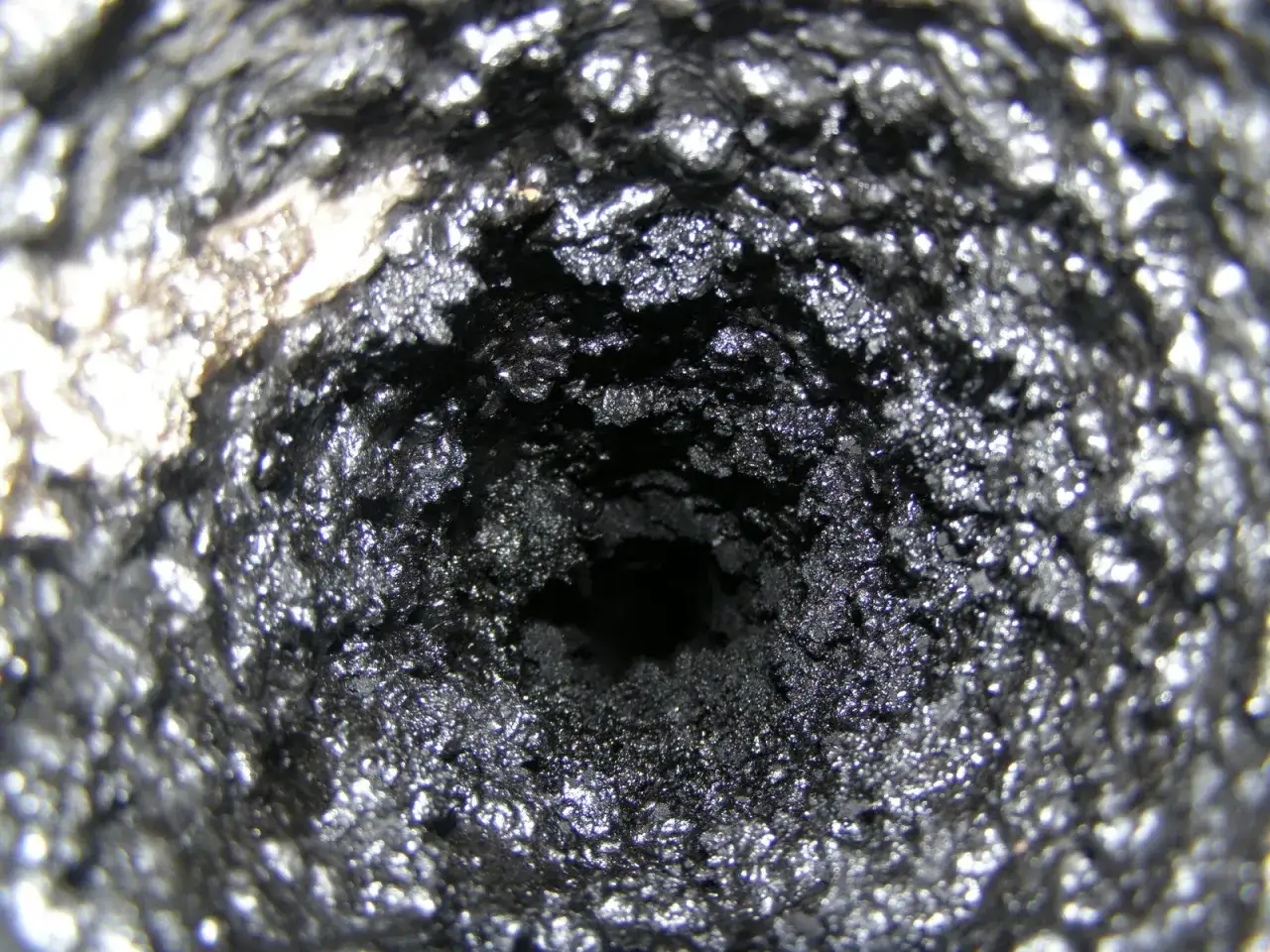 Zatkany komin z grubą warstwą sadzy. Dowiedz się, jak usunąć smołę z pieca i komina, by zapewnić bezpieczeństwo.