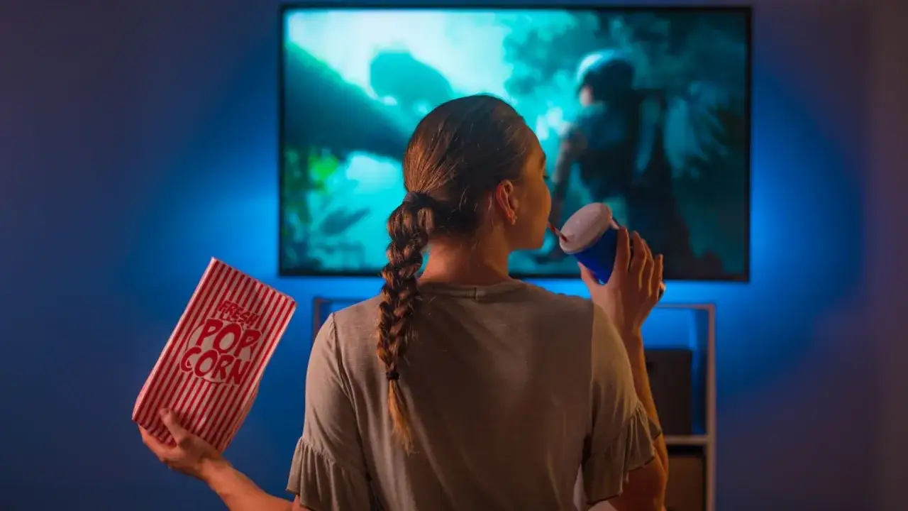 Osoba zastanawiająca się przed telewizorem, z pytajnikami