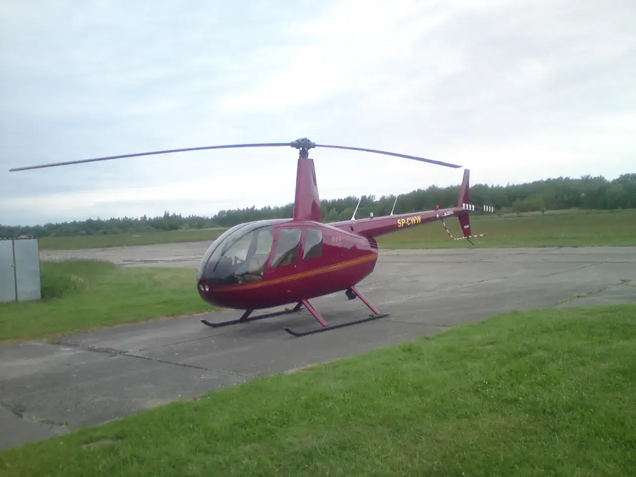 Czerwony helikopter Robinson R44 na płycie lotniska. Czy w Kołobrzegu jest lotnisko? Tak, wygląda na to, że tak!