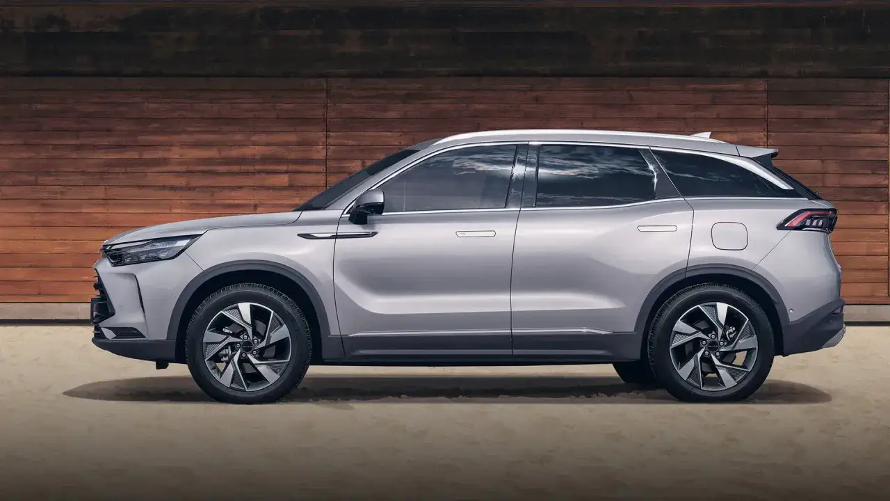 Srebrny chiński SUV za 77 tys. zł prezentuje się nowocześnie na tle drewnianej ściany.