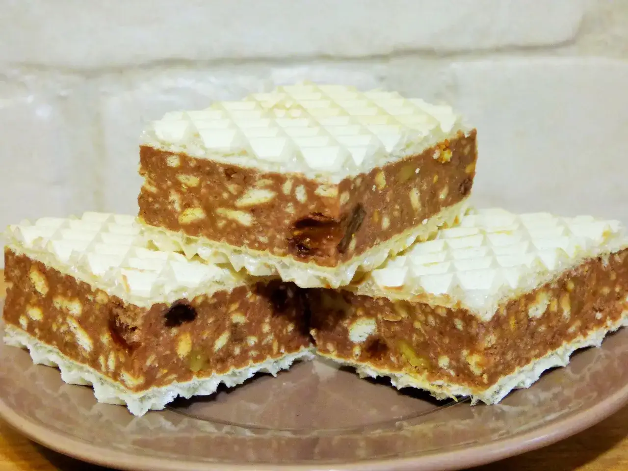 Słodkie wafle z masą z mleka w proszku, ciastek i orzech&oacute;w, ułożone na talerzu.