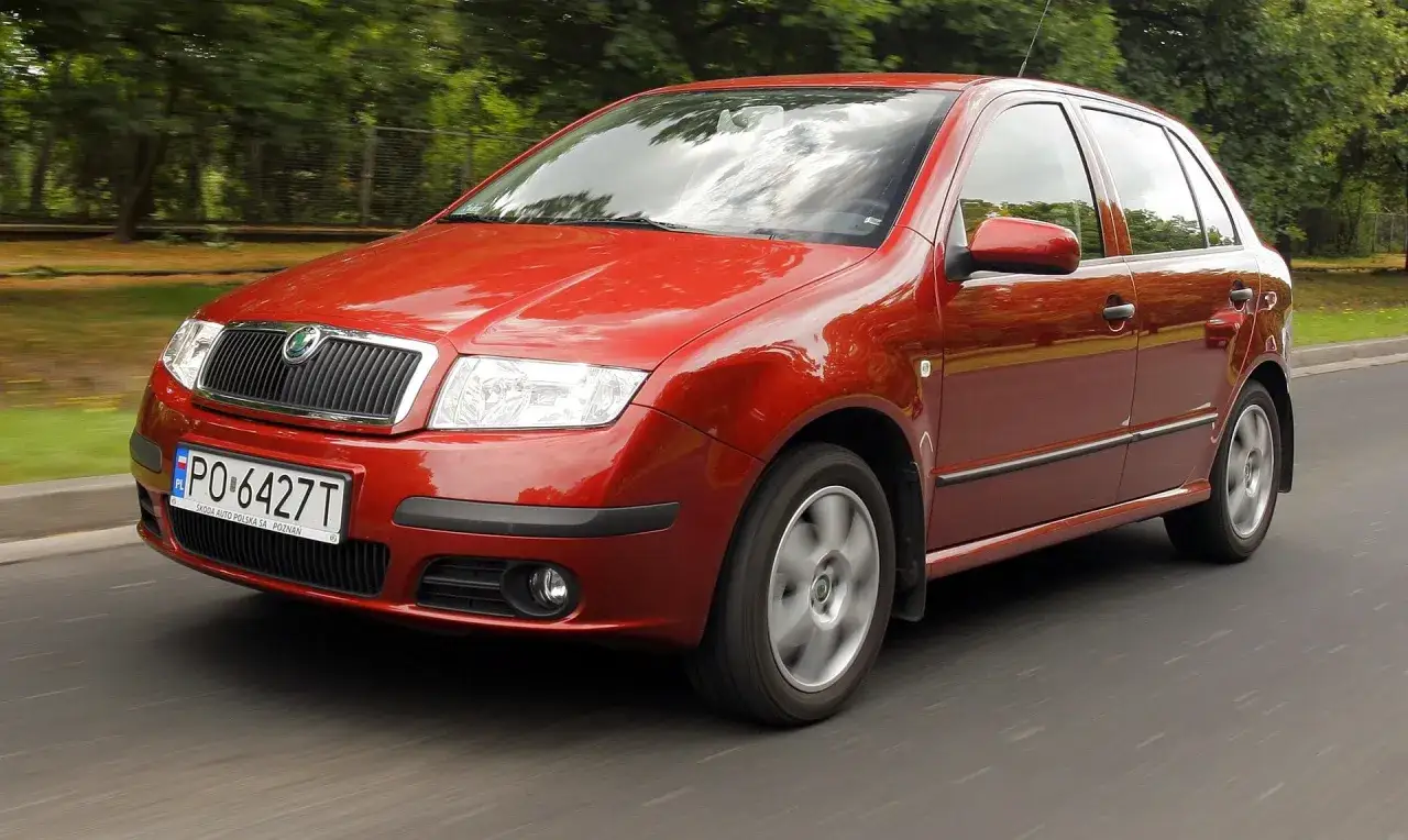 Czerwona Skoda Fabia 1 w ruchu, z widocznym numerem rejestracyjnym PO-6427T.