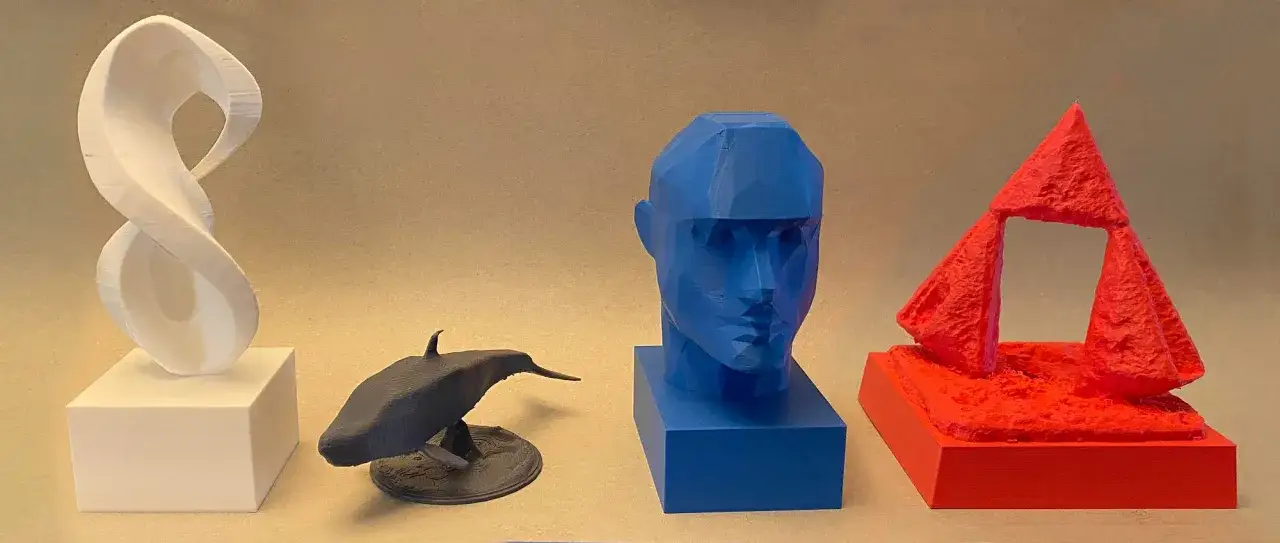 Gotowe projekty z drukarki 3D: biała wstęga, czarny wieloryb, niebieski biust i czerwona konstrukcja.