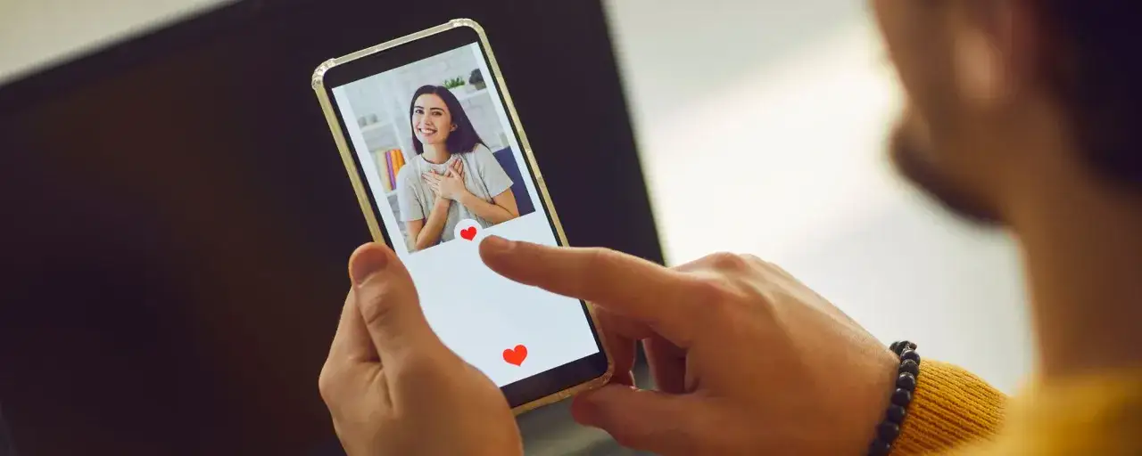 Mężczyzna przegląda profile na Tinderze, szukając tej jedynej. Jak znaleźć kogoś na Tinderze? Wystarczy swipe'ować w prawo!