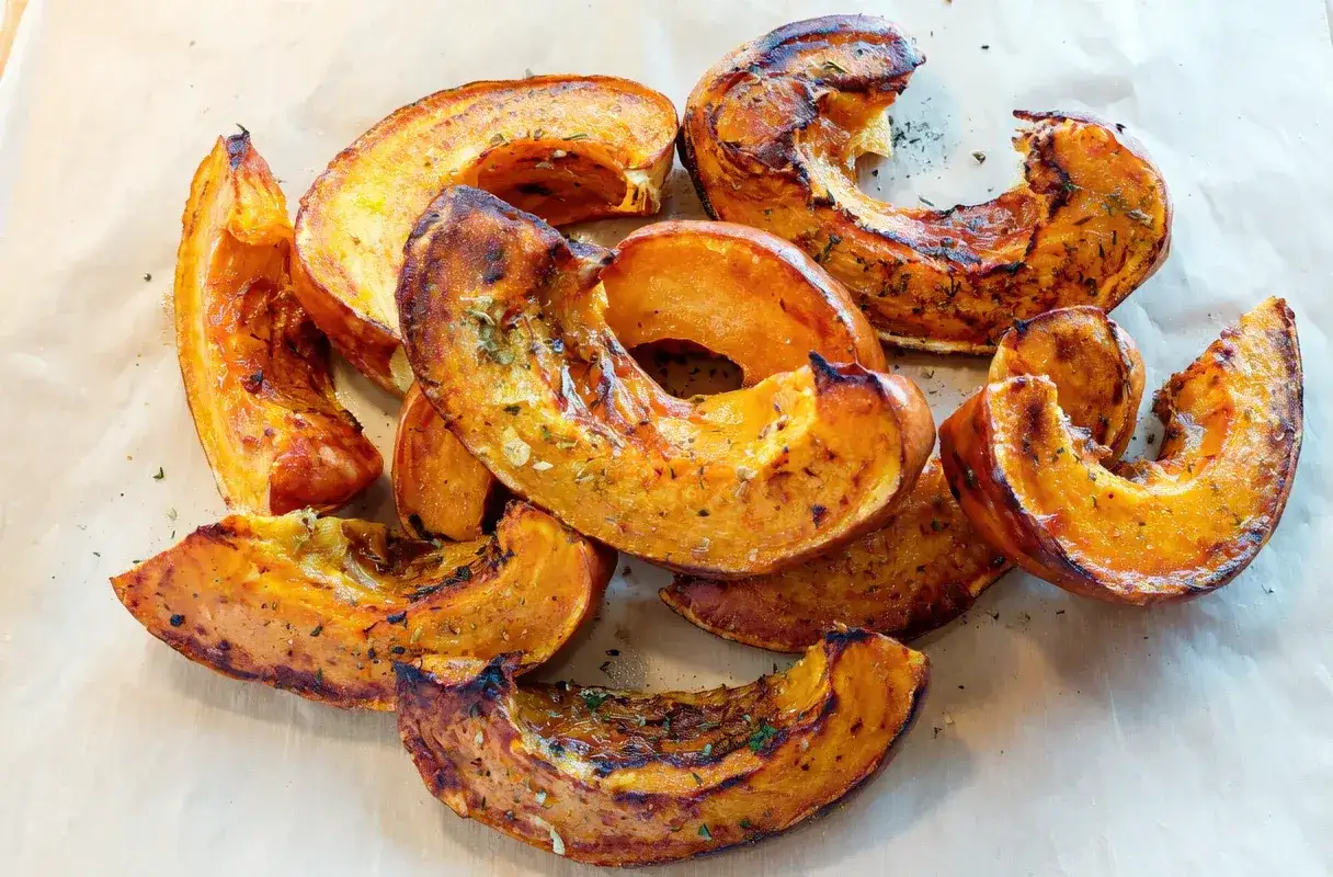 Pieczone kawałki dyni, przyprawione ziołami, idealne jako inspiracja, co ugotować z dyni.