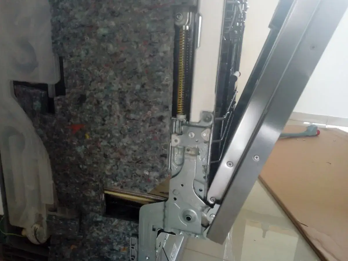 Mechanizm mocowania frontu zmywarki Beko. Widoczne sprężyny i metalowe elementy montażowe.