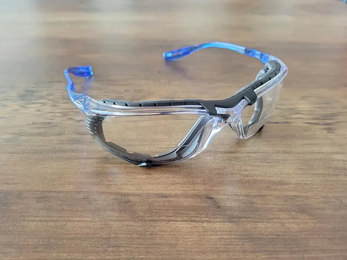 Przezroczyste okulary ochronne 3M z niebieskimi zausznikami, gotowe do pracy.