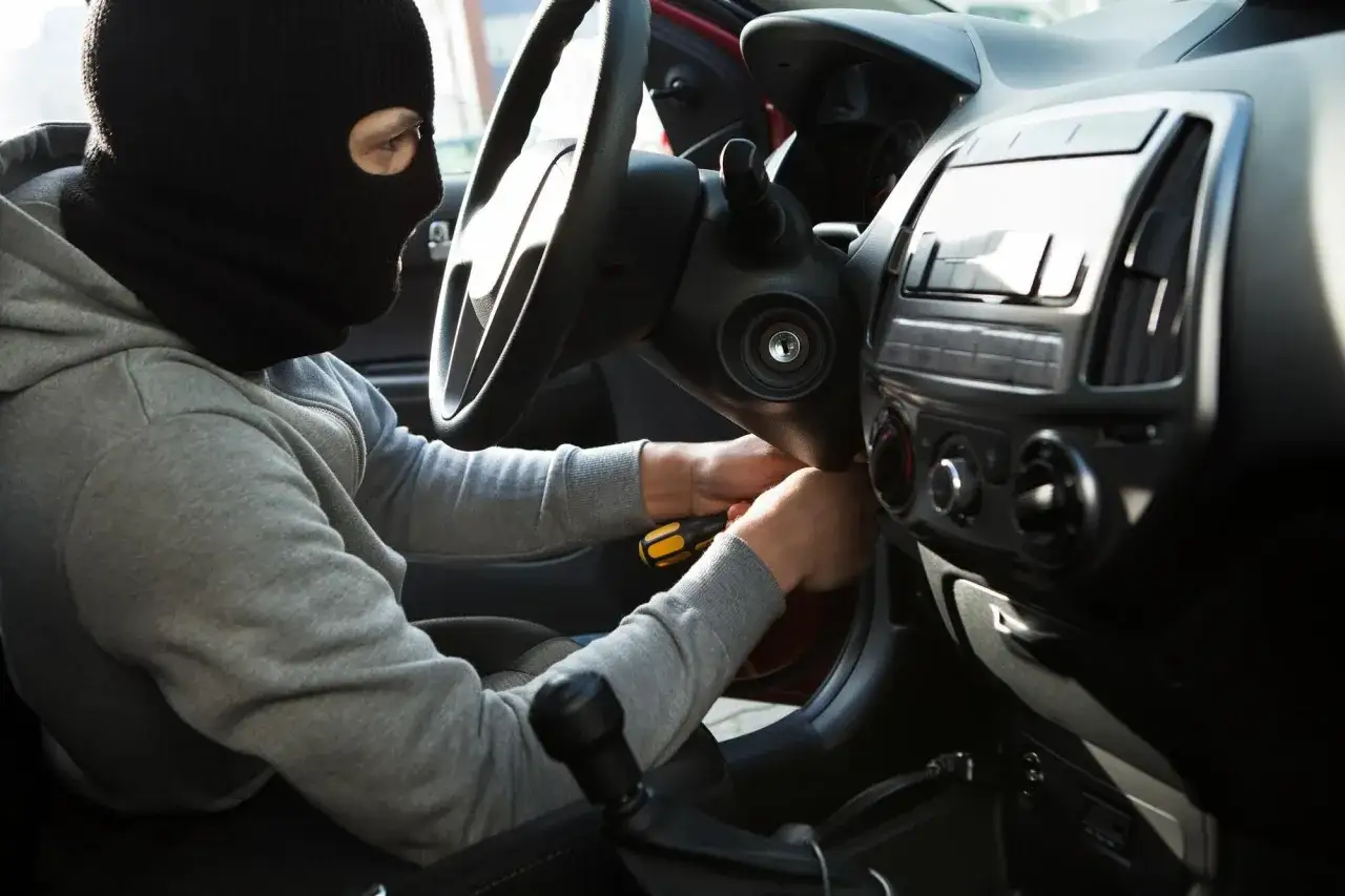 Złodziej w masce pr&oacute;buje uruchomić auto. Zastanawiasz się, ile zwraca ubezpieczyciel za skradzione auto?