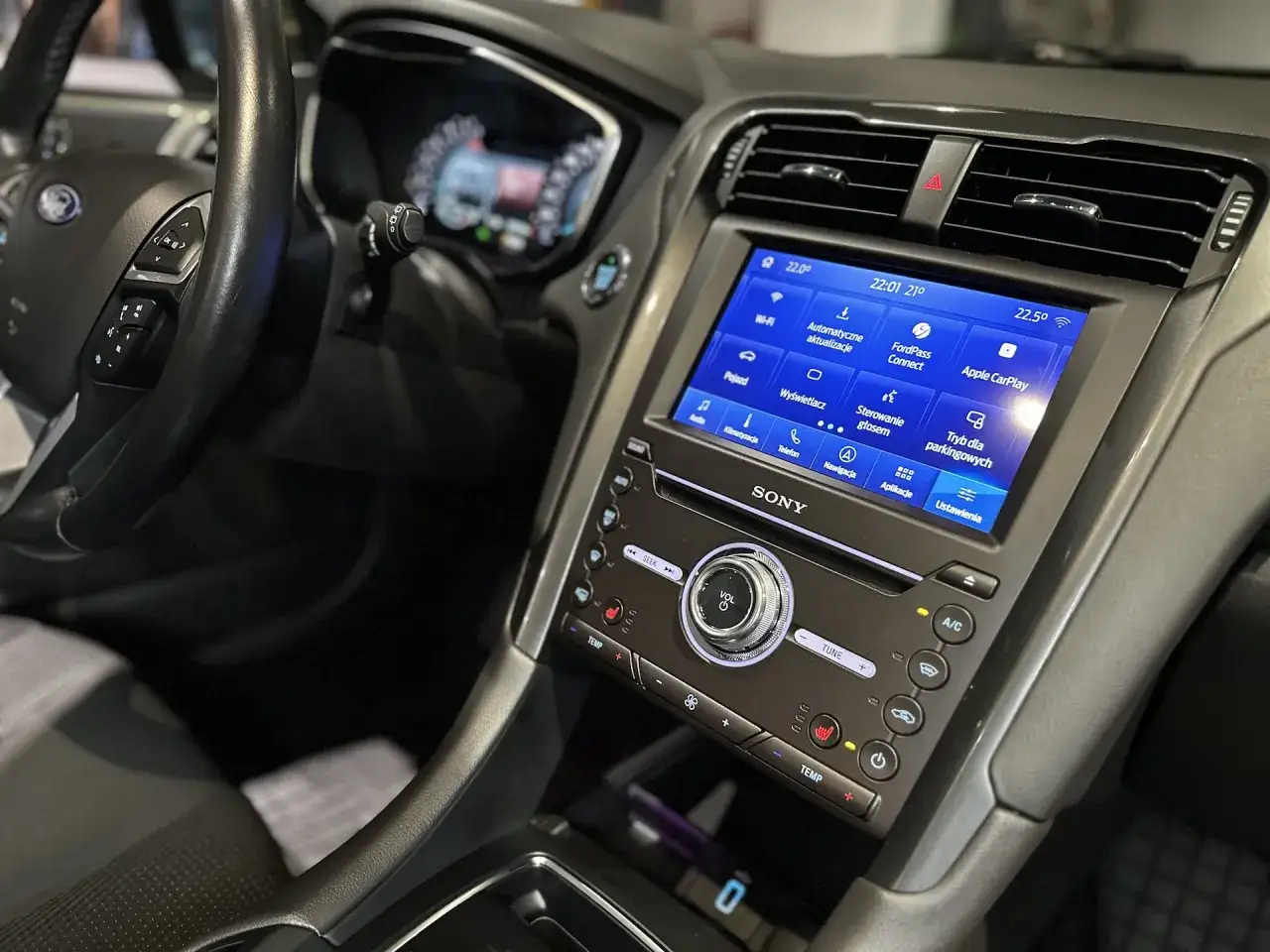 Wnętrze Forda Mondeo MK5 z ekranem dotykowym systemu multimedialnego, kierownicą i panelem klimatyzacji.