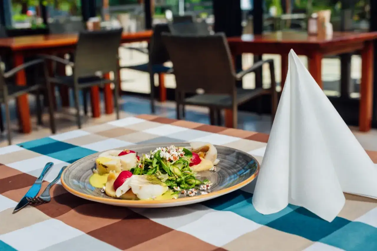 Eleganckie danie rybne na talerzu, serwetka i sztućce. Idealne miejsce, gdzie zjeść w Krynicy Morskiej.