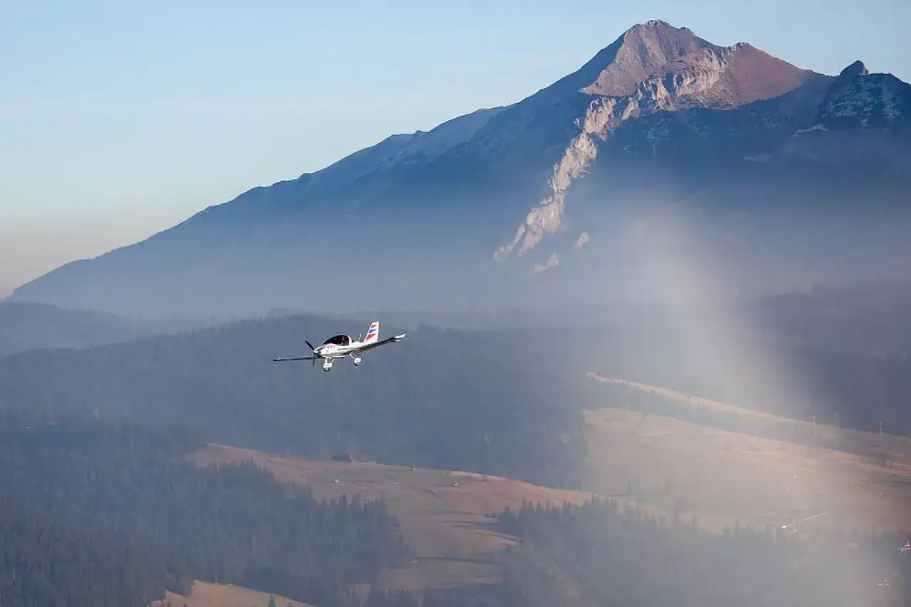 Mały samolot przelatuje nad mglistymi dolinami, podziwiając majestatyczne tatry z samolotu.