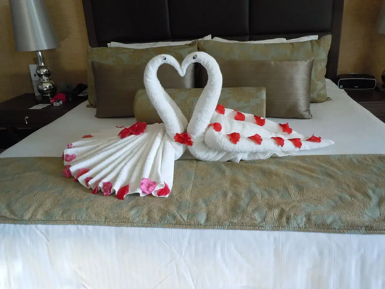 łabędź z ręcznika na ł&oacute;żku hotelowym