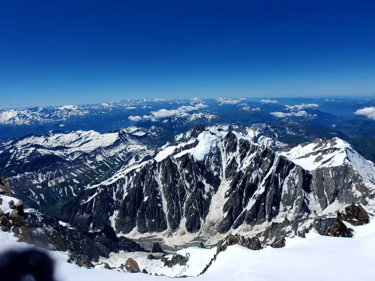 Widok z najwyższego szczytu Alp na ośnieżone pasma górskie i błękitne niebo.