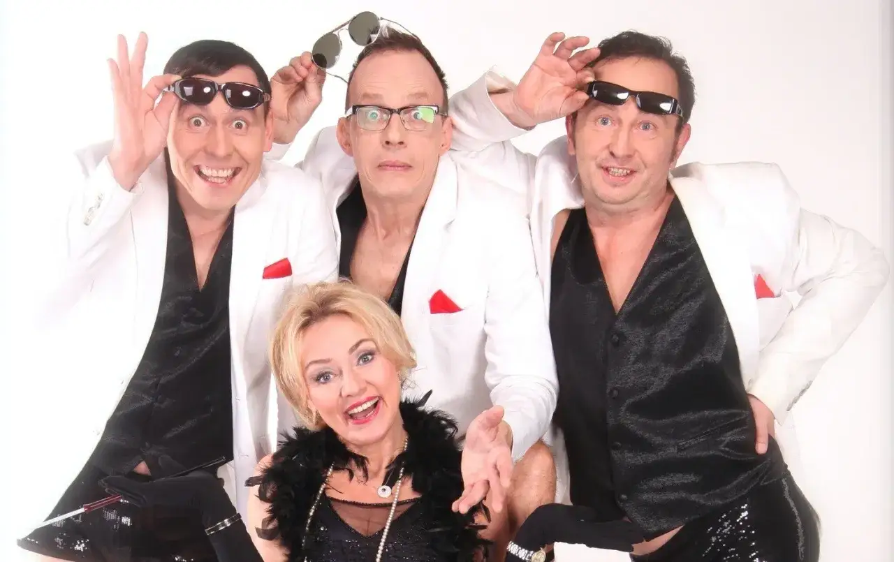 Trzech panów w białych marynarkach i czarnych kamizelkach, z okularami na nosach i głowach, oraz pani w piórach i koralach. Czy kabaret pod Wyrwigroszem jeszcze istnieje?