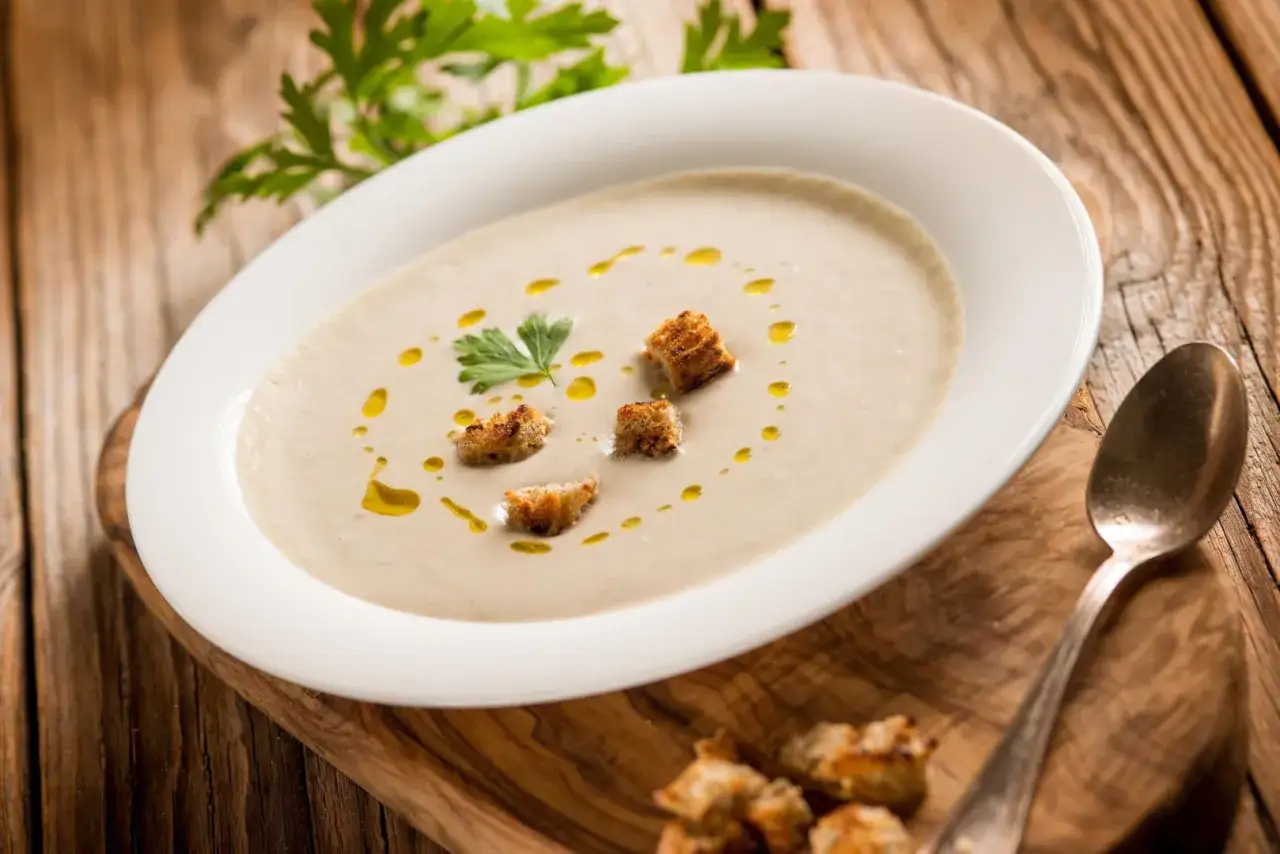 Kremowa zupa z porów z grzankami i oliwą, udekorowana natką pietruszki. Idealna na chłodne dni.