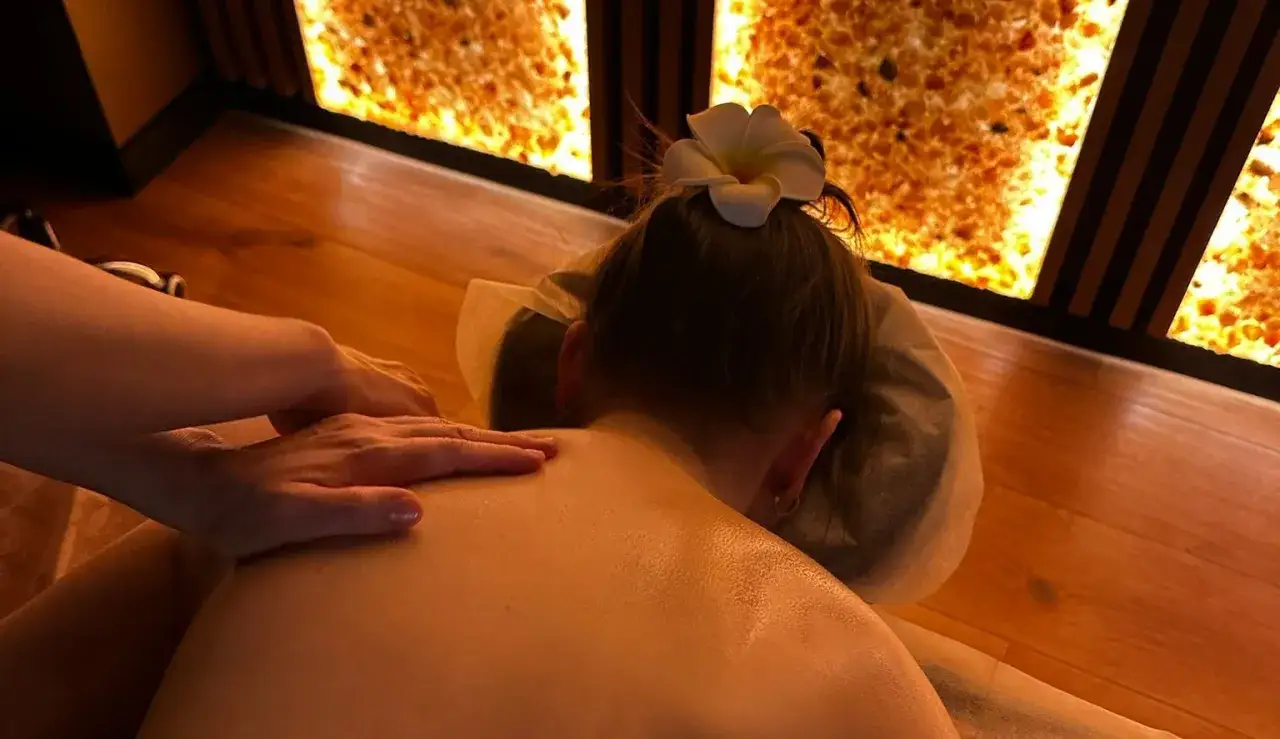 Relaksacyjny masaż pleców z użyciem olejku. Dłonie terapeuty delikatnie przesuwają się po skórze, przynosząc ulgę.