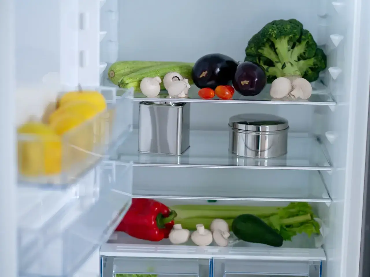 W lodówce świeże warzywa: cukinia, bakłażany, pomidorki, brokuł, papryka, seler, awokado, pieczarki. Metalowe pojemniki mogą być tym, co pochłania zapachy w lodówce.