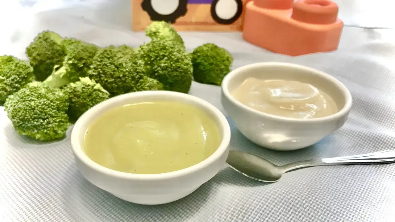 Dwa miseczki z puree z brokuł&oacute;w i innym warzywem, idealne jako pierwsze pokarmy dla niemowląt po 4 miesiącu. Obok świeże r&oacute;życzki brokułu.