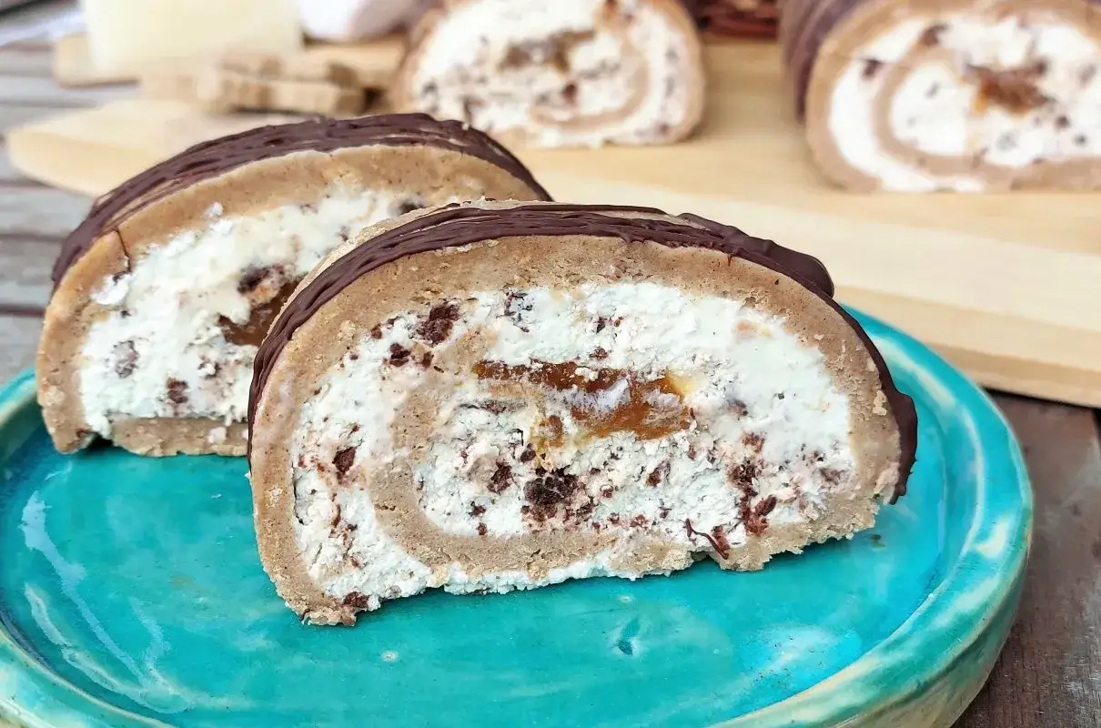 Pyszna rolada serowa z kawałkami czekolady i kandyzowanymi owocami, polana czekoladą.