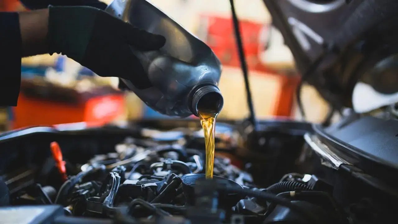 Mechanik wlewa nowy olej do silnika. Dowiedz się, ile kosztuje wymiana oleju w samochodzie.