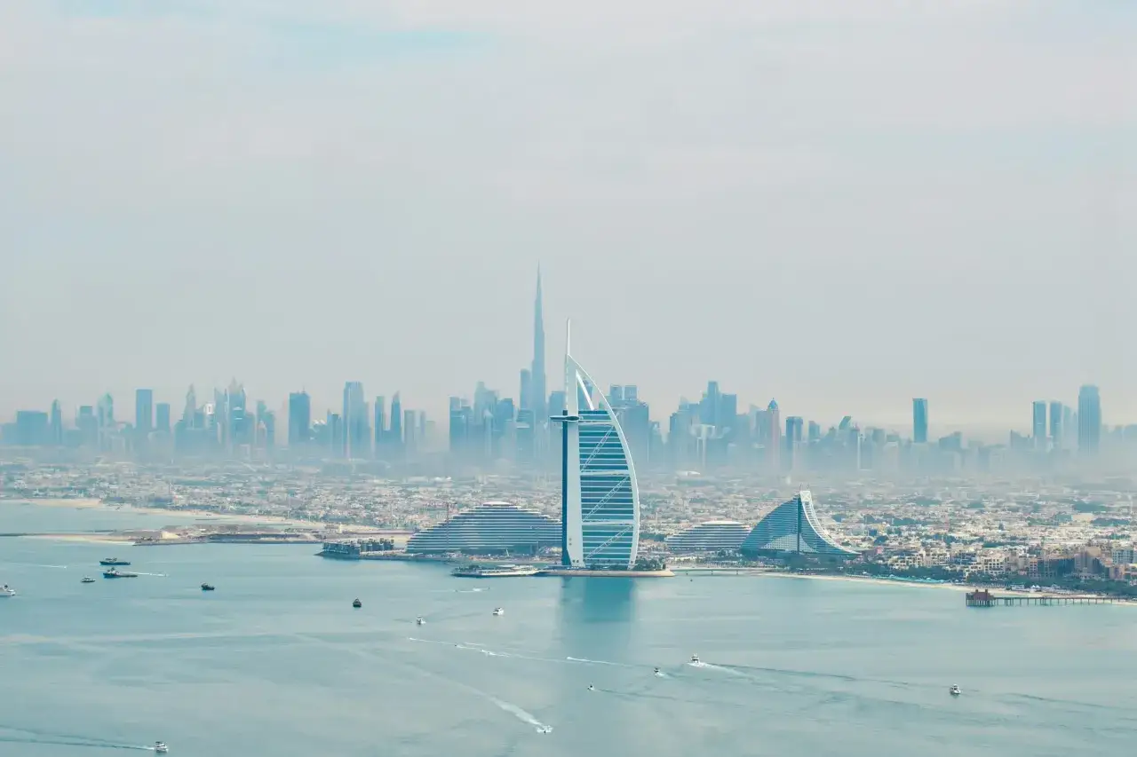 Widok na Dubaj z drapaczami chmur i hotelem w kształcie żagla. Woda pełna łodzi. Czy w Dubaju jest bezpiecznie? Tak, to nowoczesne i bezpieczne miasto.