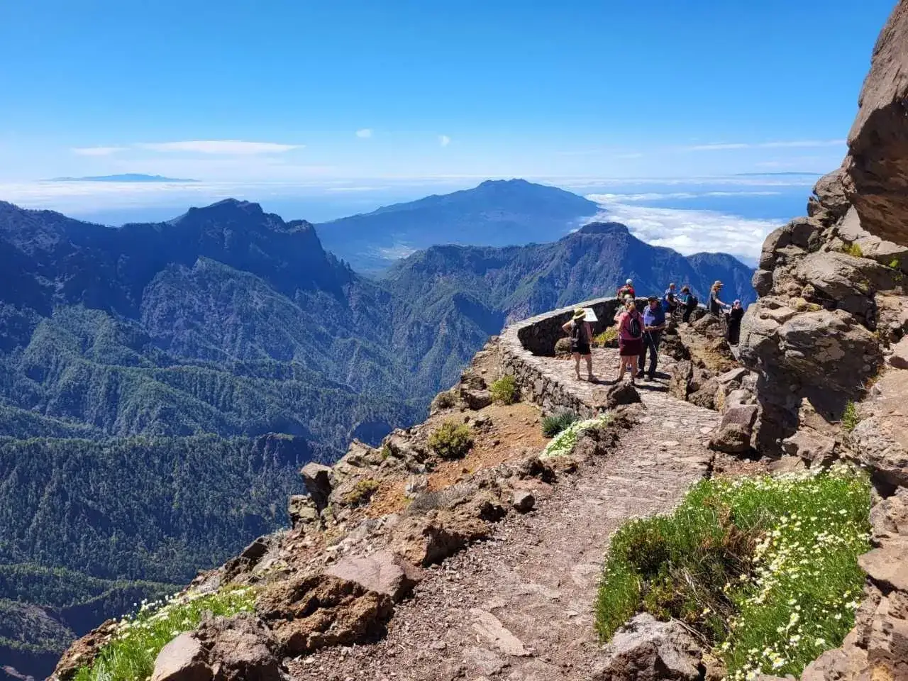 Grupa turystów podziwia zapierający dech w piersiach widok z punktu widokowego na **La Palma wyspa**. Górzyste krajobrazy i morze chmur tworzą niezwykłą panoramę.