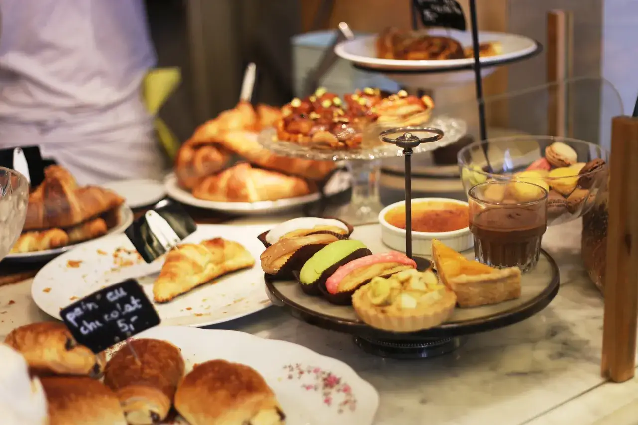 Słodkości na stole: rogaliki, babeczki, makaroniki i deser crème brûlée. Idealne na popołudniową kawę, może nawet z kawałkiem charlotte po polsku.