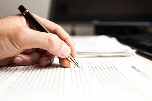 osoba pisząca oficjalny dokument przy biurku