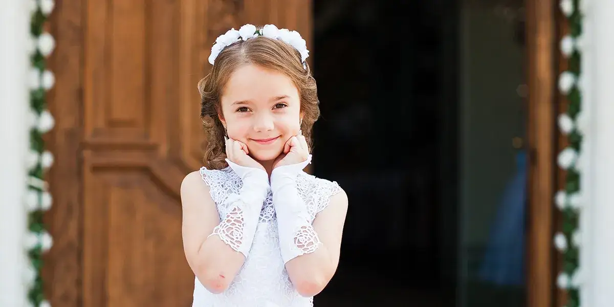 Dziecko w stroju komunijnym z hostią