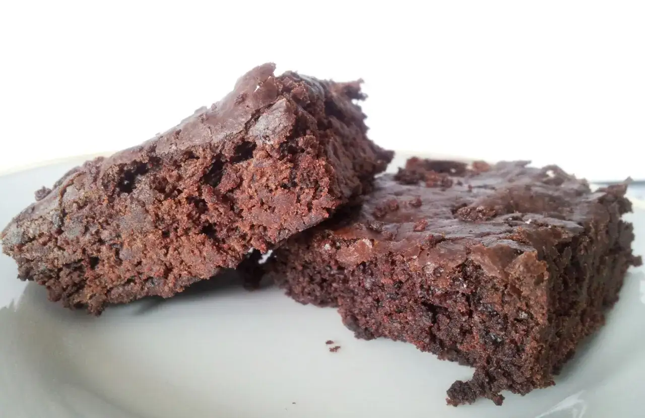 Dwa wilgotne, czekoladowe brownie bez jajek na białym talerzu. Idealne dla łasuch&oacute;w!