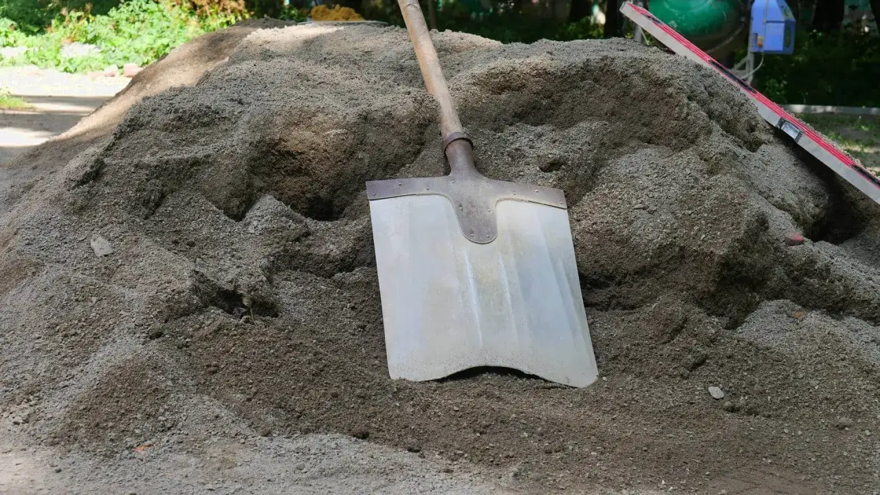 Stos suchego betonu, łopata i poziomica. Cena 1m3 suchego betonu zależy od składu i dostawcy.