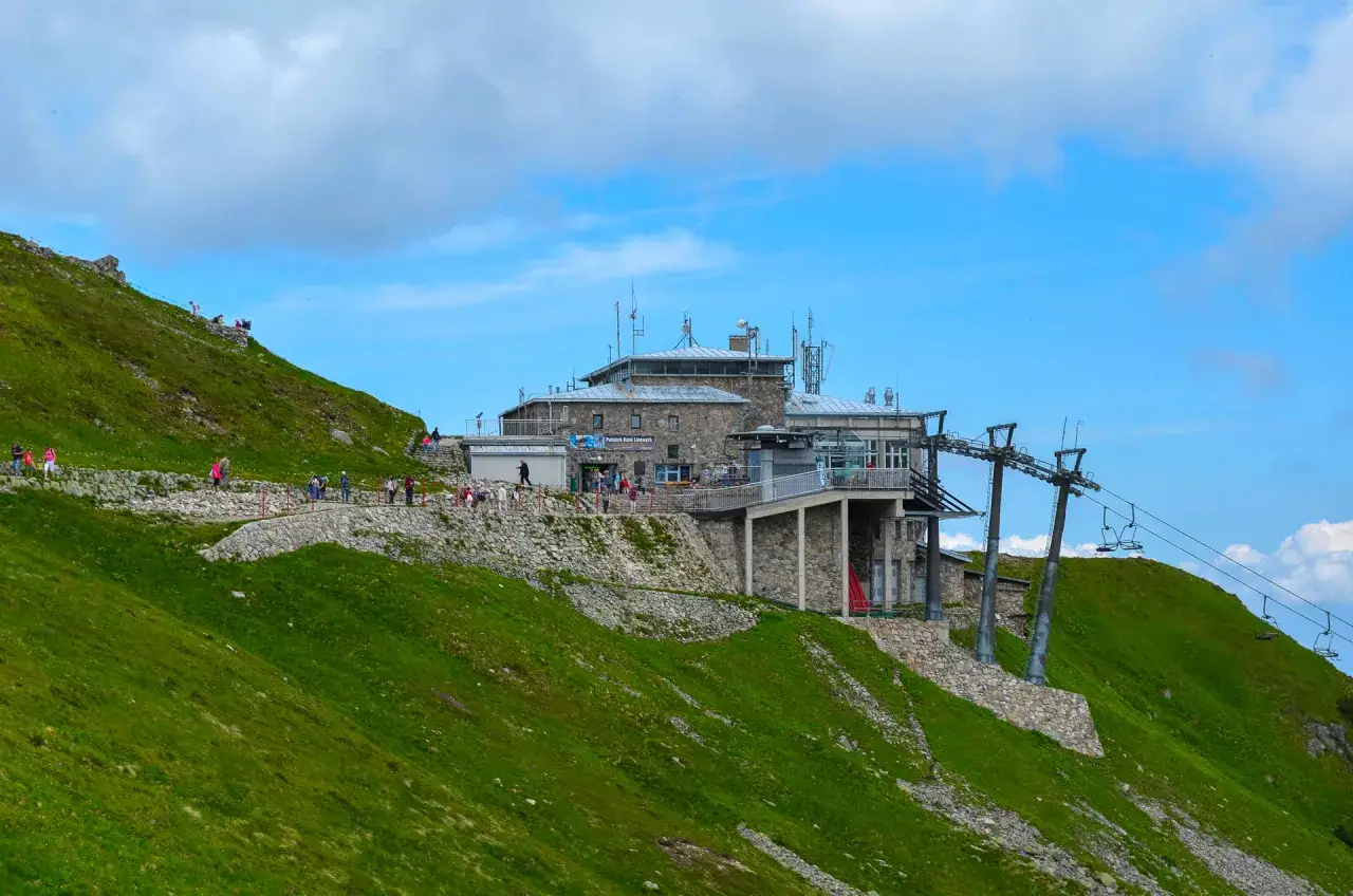 Turyści na zielonych zboczach Tatr, w pobliżu g&oacute;rnej stacji kolejki na Kasprowy Wierch.