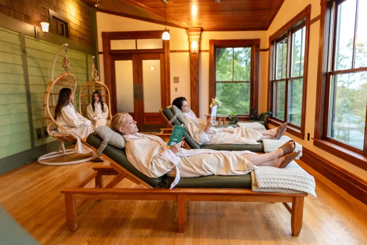 Relaks w spa: kobiety w szlafrokach odpoczywają na leżakach, czytając książki i podziwiając widok za oknem.