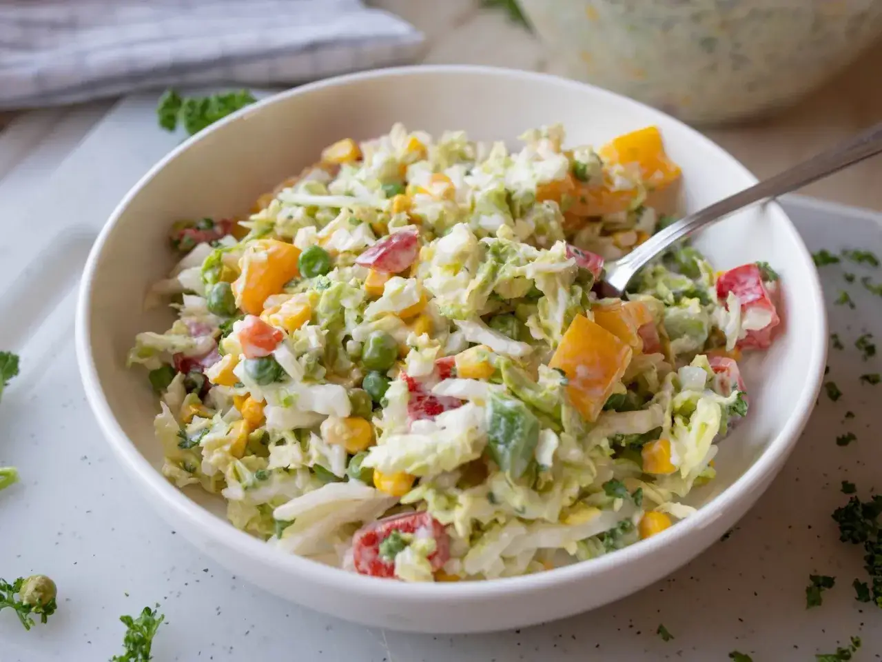 Pyszna sur&oacute;wka z kapusty pekińskiej z kukurydzą, papryką i groszkiem, polana kremowym sosem.