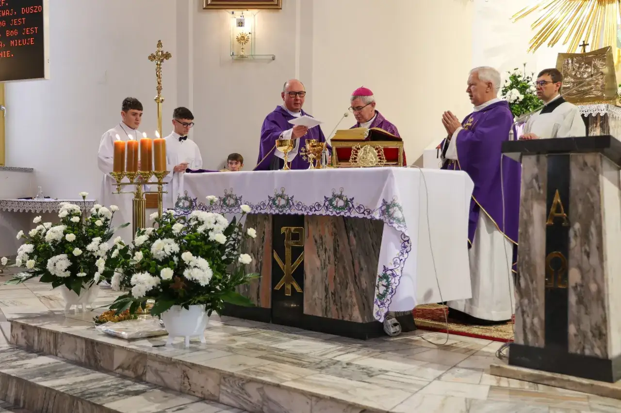 Uroczystość konsekracji kościoła: kapłani w purpurowych szatach odprawiają nabożeństwo przy ołtarzu, ministranci asystują.