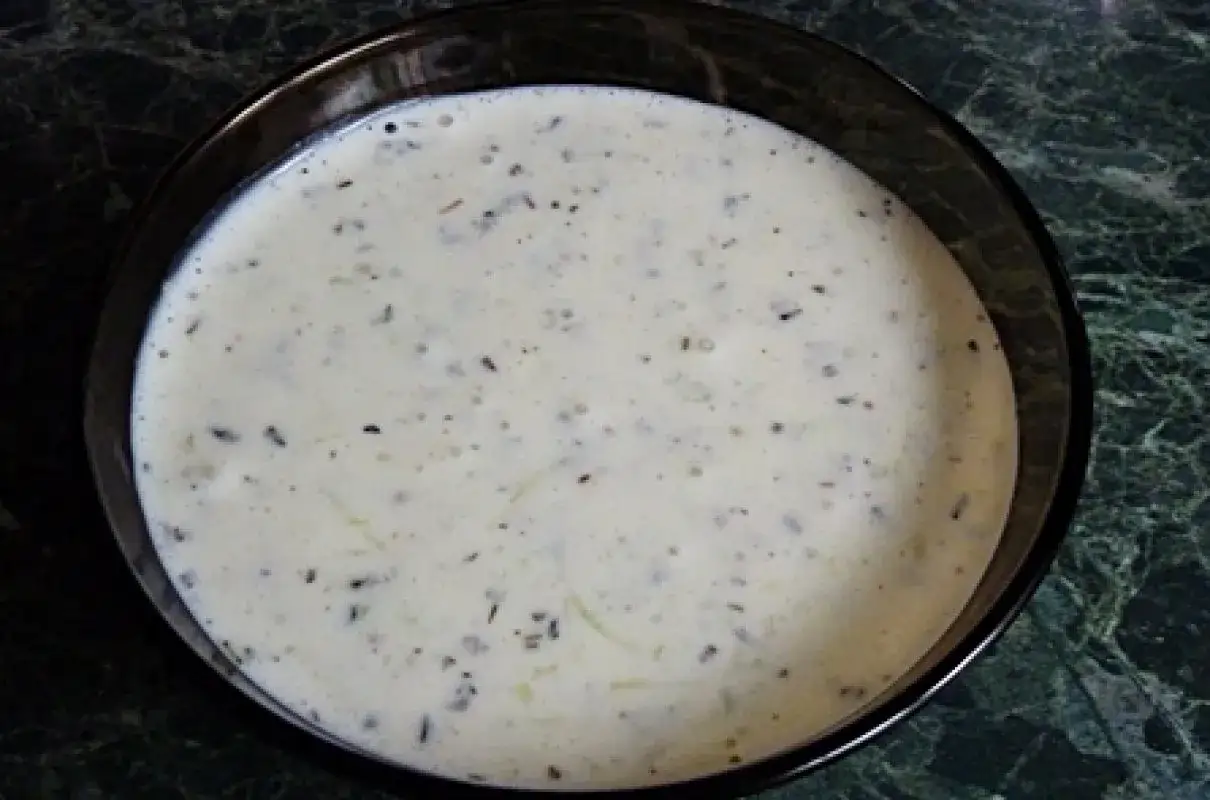 Kremowy sos mieszany do kebaba, z widocznymi ziołami i przyprawami, w ciemnej miseczce.