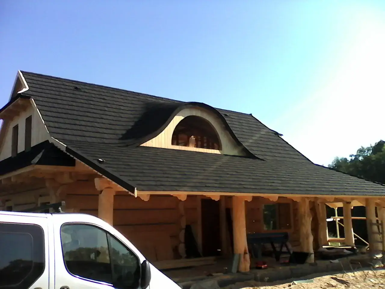 Drewniany dom w budowie z charakterystycznym, falującym dachem. Na dachu widoczne jest okno w kształcie bawolego oka.