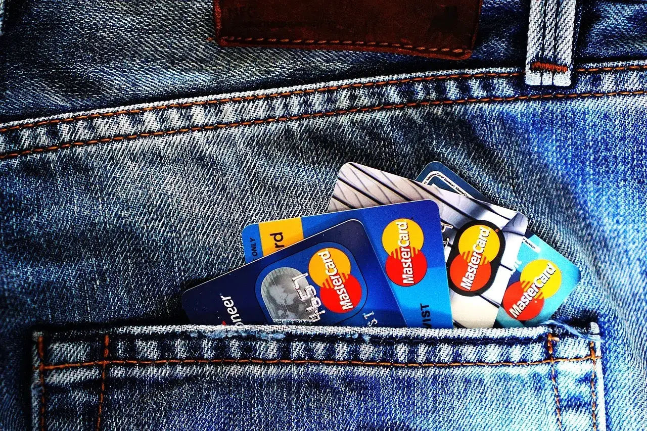 Kilka kart płatniczych, w tym Mastercard, w tylnej kieszeni dżins&oacute;w. Zastanawiasz się, preautoryzacja co to?
