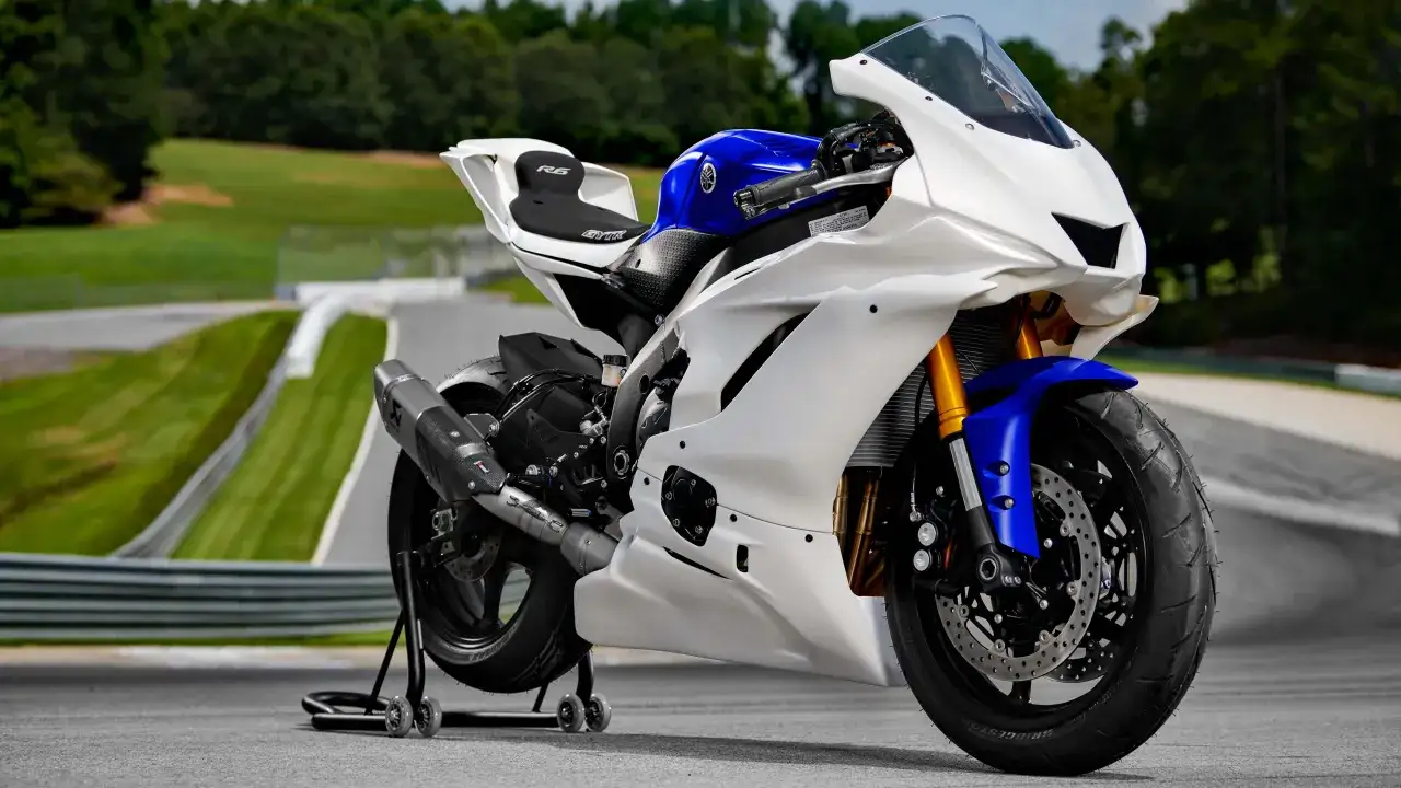 Biało-niebieski motocykl sportowy Yamaha YZF R6 na torze wyścigowym, gotowy do jazdy.