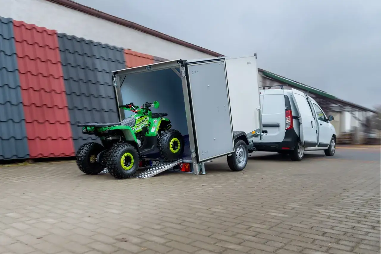 Zielony quad wjeżdża na przyczepkę, gotowy do transportu. Ubezpieczenie przyczepki zapewni spokój podczas podróży.