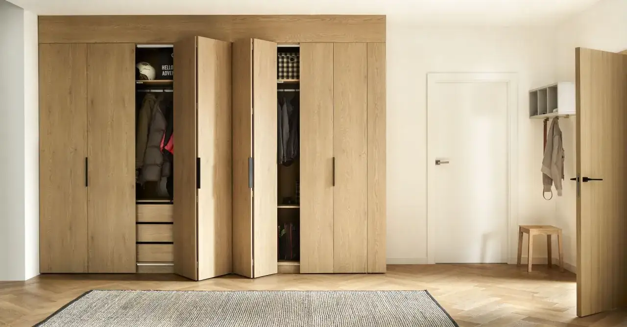 Drewniana zabudowa z uchylnymi drzwiczkami to świetny pomysł na ścianę w przedpokoju. W środku wieszaki i szuflady na ubrania.