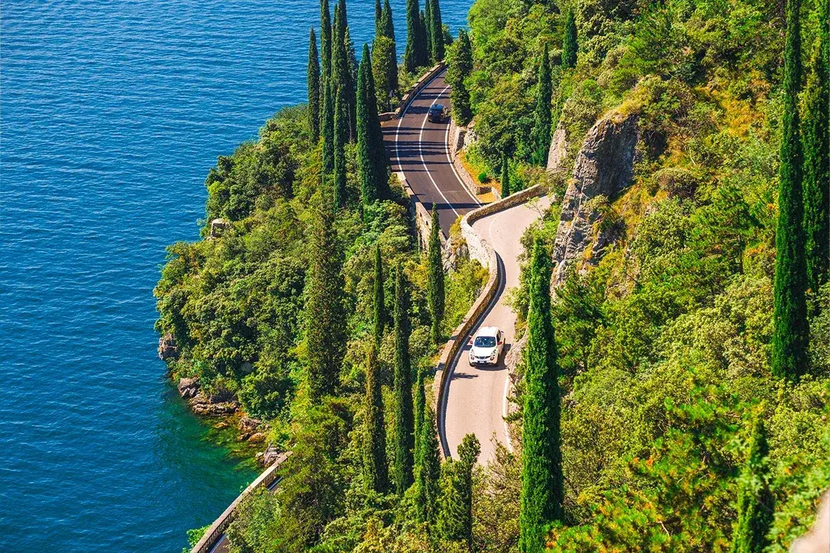 Droga wije się przy skalistym wybrzeżu, otoczona cyprysami. Widok z 