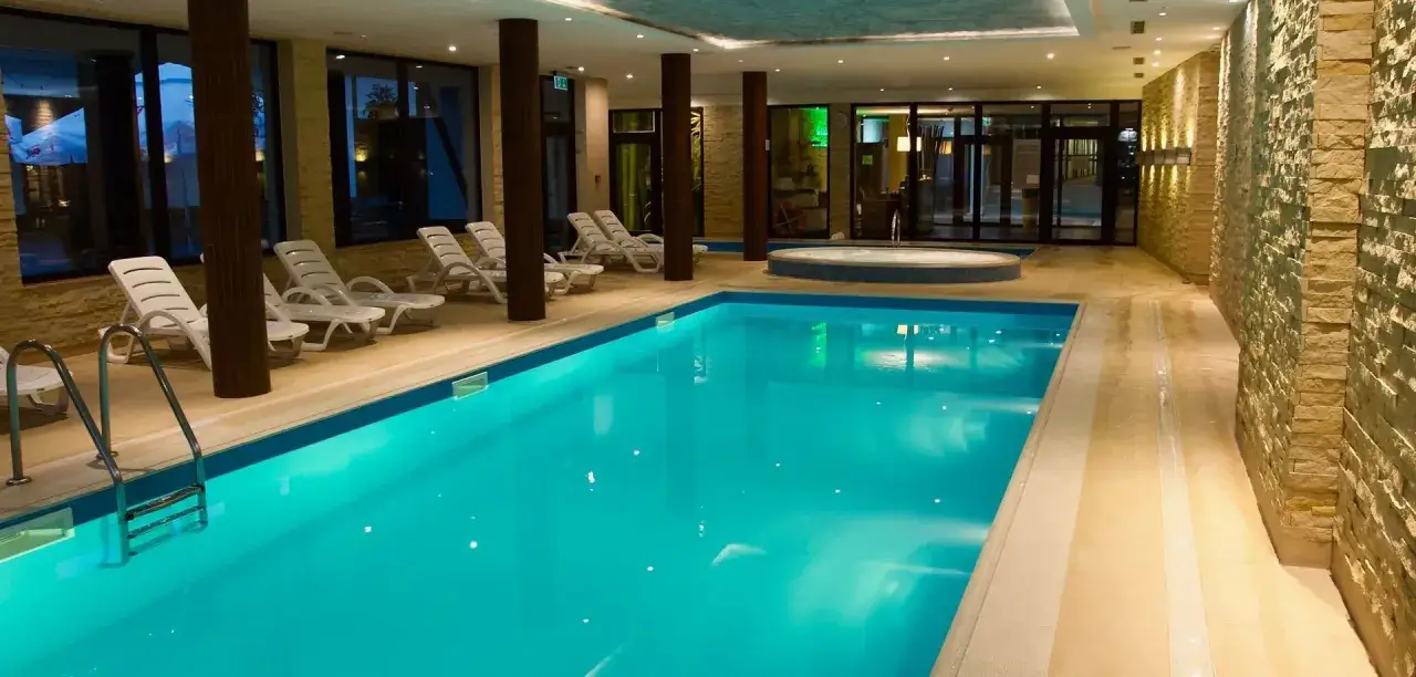 Basen i jacuzzi w hotelu, idealne miejsce na relaks po mikołajkach. Leżaki czekają na gości.