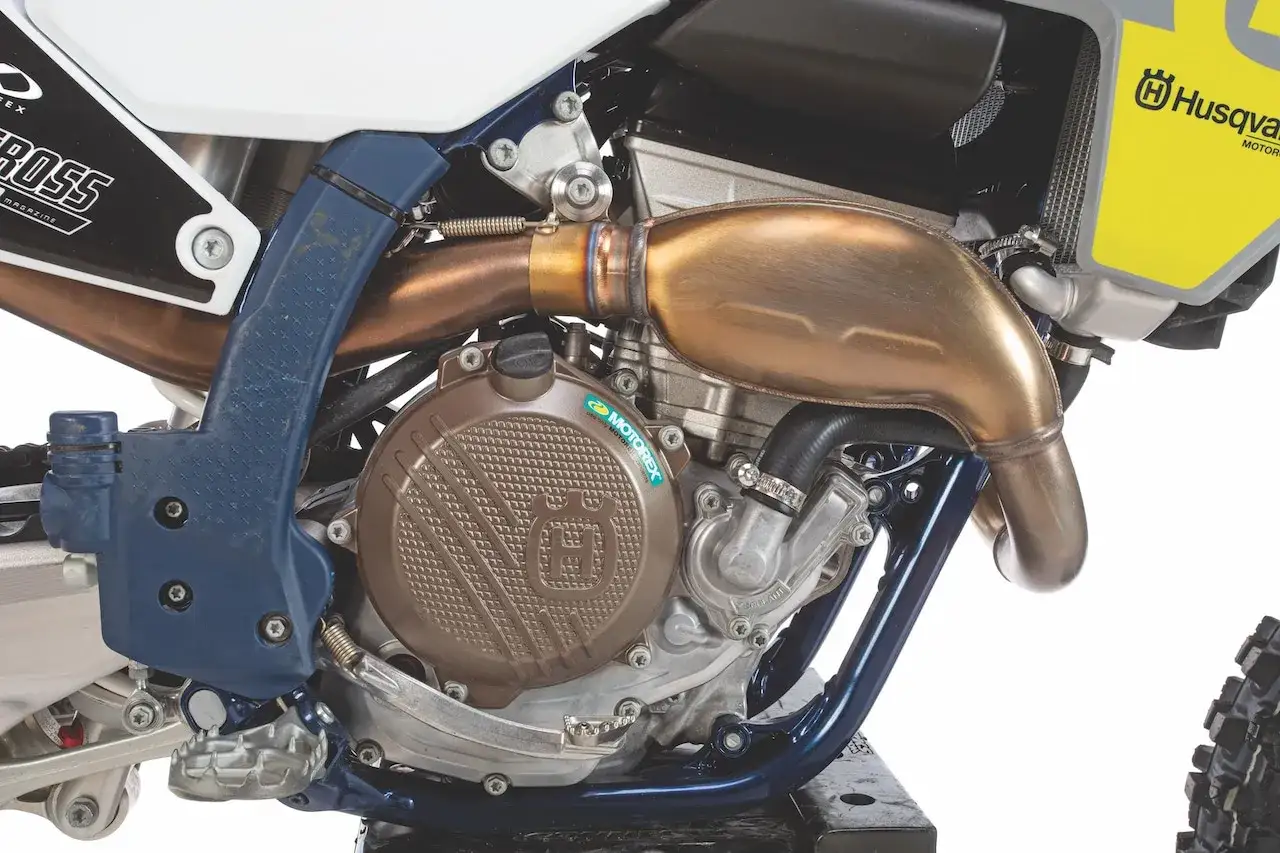 Silnik motocykla Husqvarna FC 250 z miedzianym wydechem i brązową pokrywą.