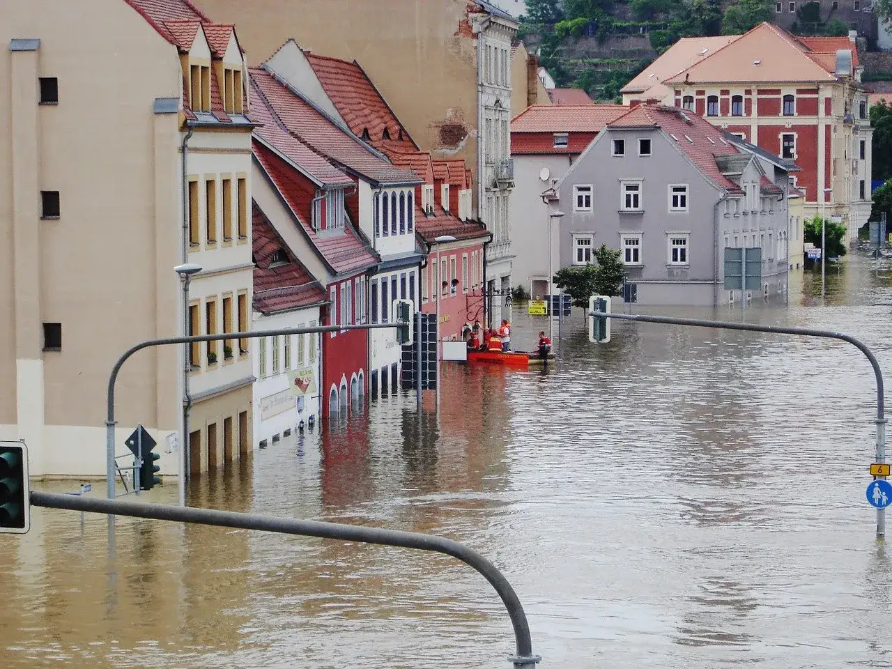 Zalane miasto, ratownicy na łodzi. Warto mieć ubezpieczenie mieszkania od zalania, by uniknąć takich strat.
