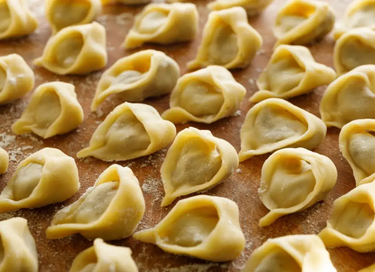 Uformowane uszka na drewnianej desce. Sekret na miękkie ciasto na uszka tkwi w odpowiednich proporcjach składników.