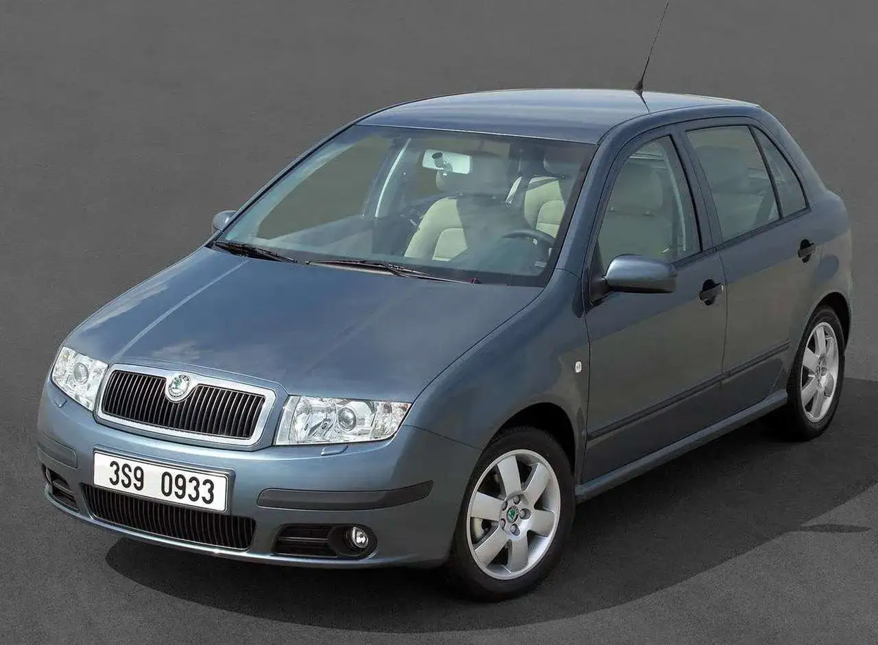 Szara Skoda Fabia 1, model z początku lat 2000, z jasnym wnętrzem, stoi na szarym tle.