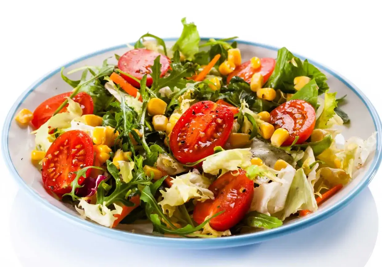 Kolorowa sałatka z rukolą, pomidorkami koktajlowymi, kukurydzą i chrupiącą sałatą lodową. Idealna na lekki posiłek.