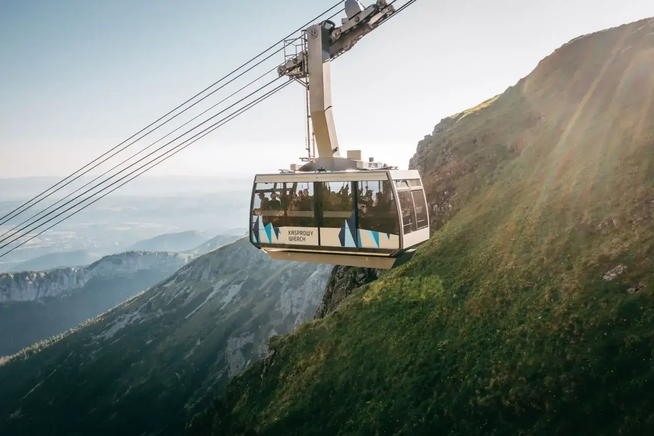 Kolejka linowa PKL Kasprowy Wierch wjeżdża na zbocze g&oacute;rskie, oferując pasażerom widok na Tatry.