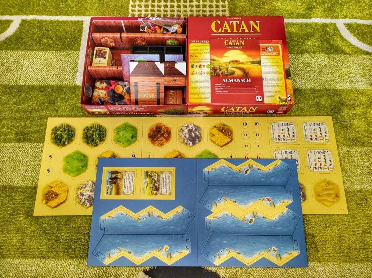 Rozłożona gra Catan wersja podróżna z elementami planszy, kartami i instrukcją.